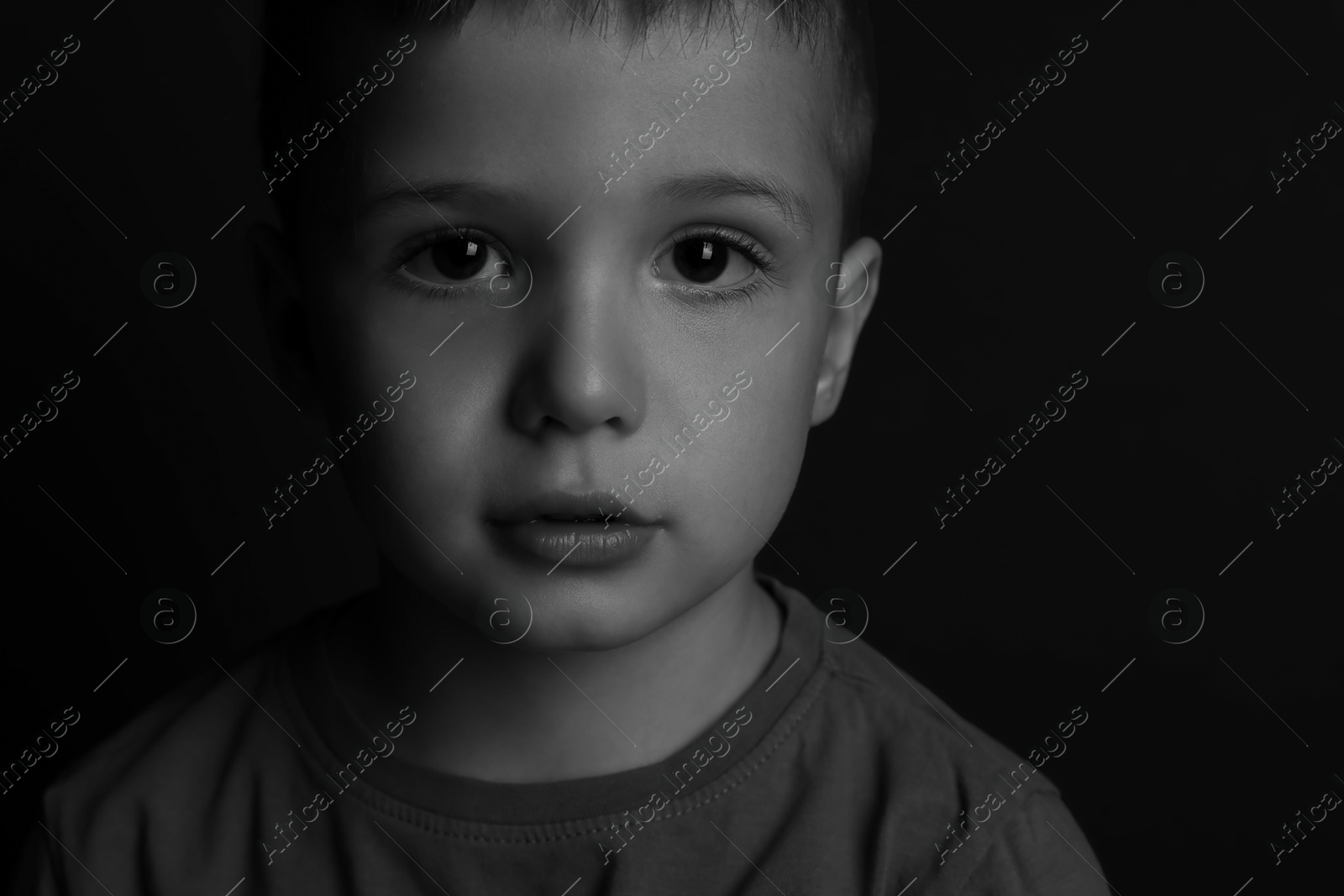 Photo of Portrait of little boy on dark background. Black and white effect