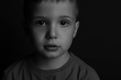 Photo of Portrait of little boy on dark background. Black and white effect