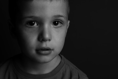 Photo of Portrait of little boy on dark background, space for text. Black and white effect