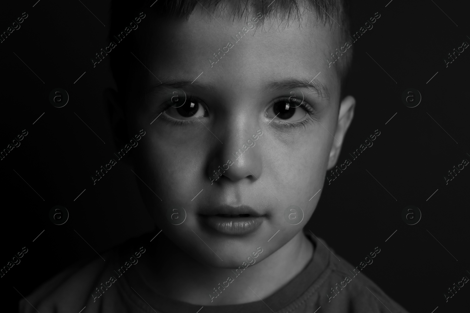 Photo of Portrait of little boy on dark background. Black and white effect