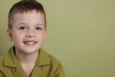 Portrait of cute little boy on green background, space for text