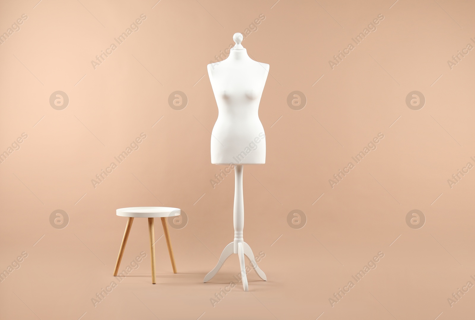 Photo of Female mannequin and stool on beige background