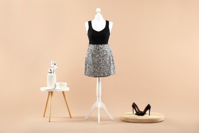 Photo of Mannequin with stylish dress, vase and shoes on beige background