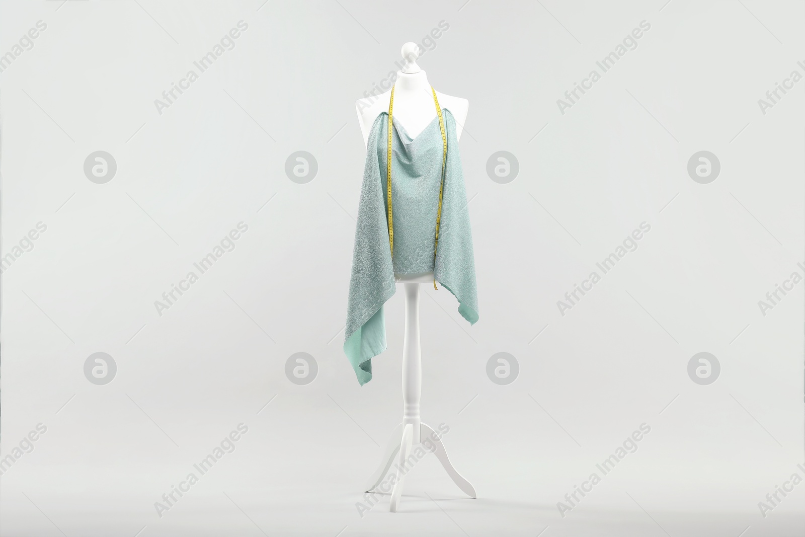 Photo of Mannequin, cloth and measuring tape on light grey background