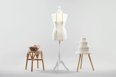 Photo of Mannequin with measuring tape and stools on light grey background