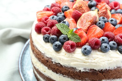 Photo of Delicious chocolate sponge cake with berries on white table, closeup