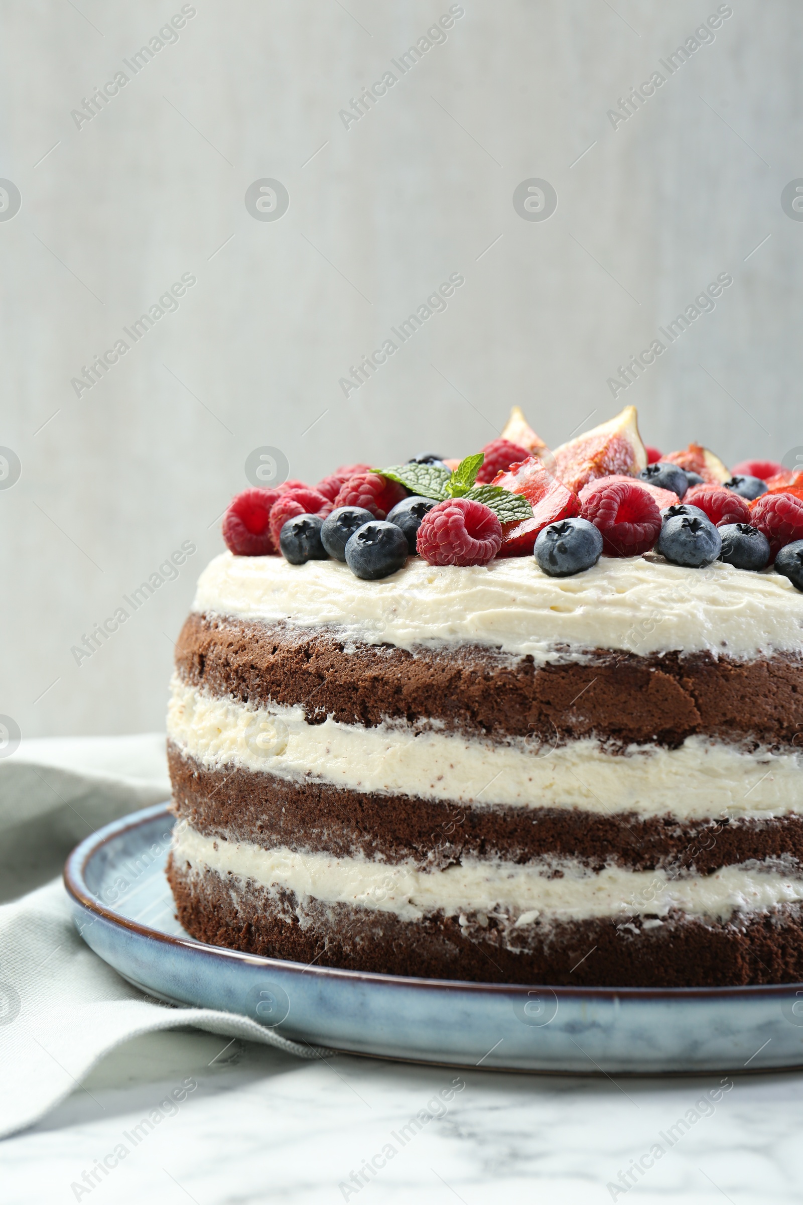 Photo of Delicious chocolate sponge cake with berries on white table, closeup