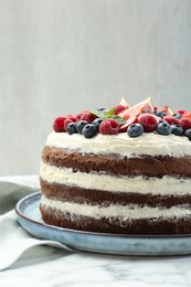 Photo of Delicious chocolate sponge cake with berries on white table, closeup