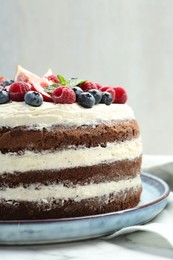 Photo of Delicious chocolate sponge cake with berries on white table, closeup