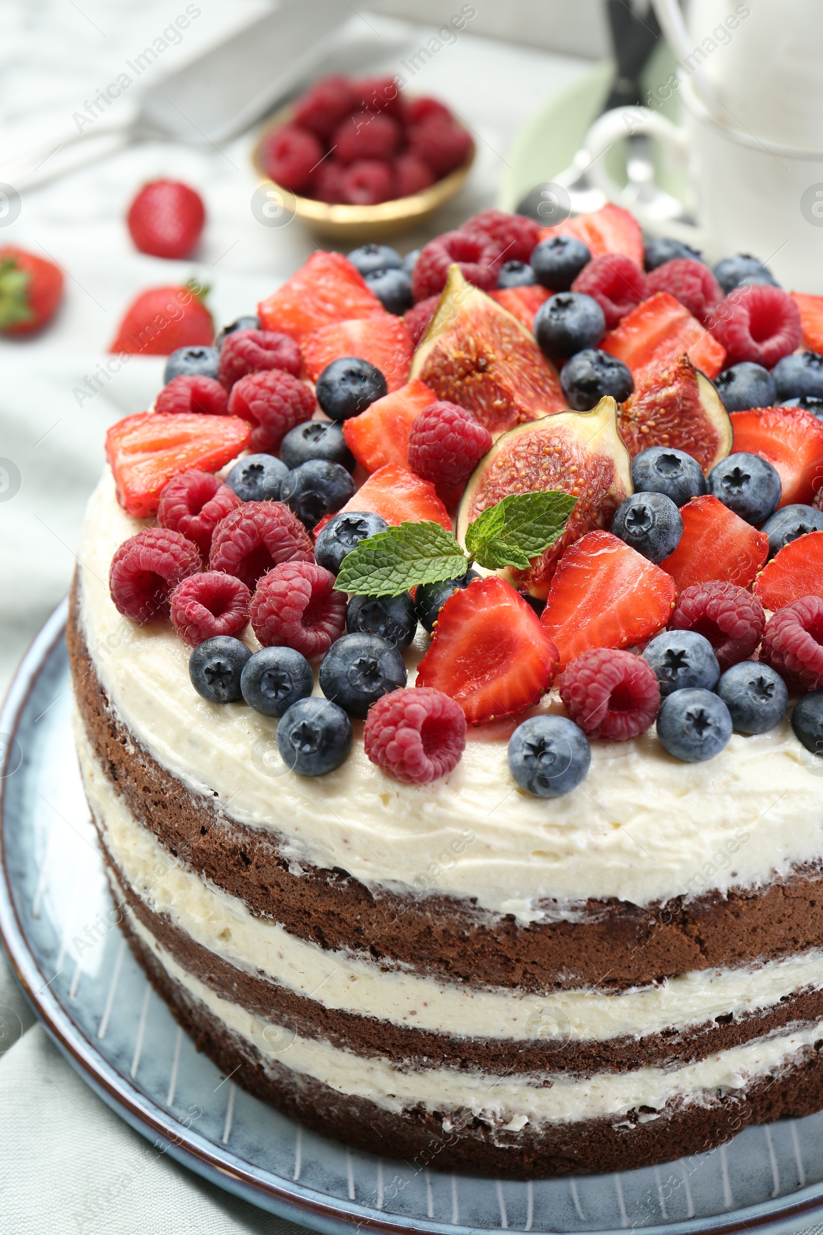 Photo of Delicious chocolate sponge cake with berries on white table, closeup