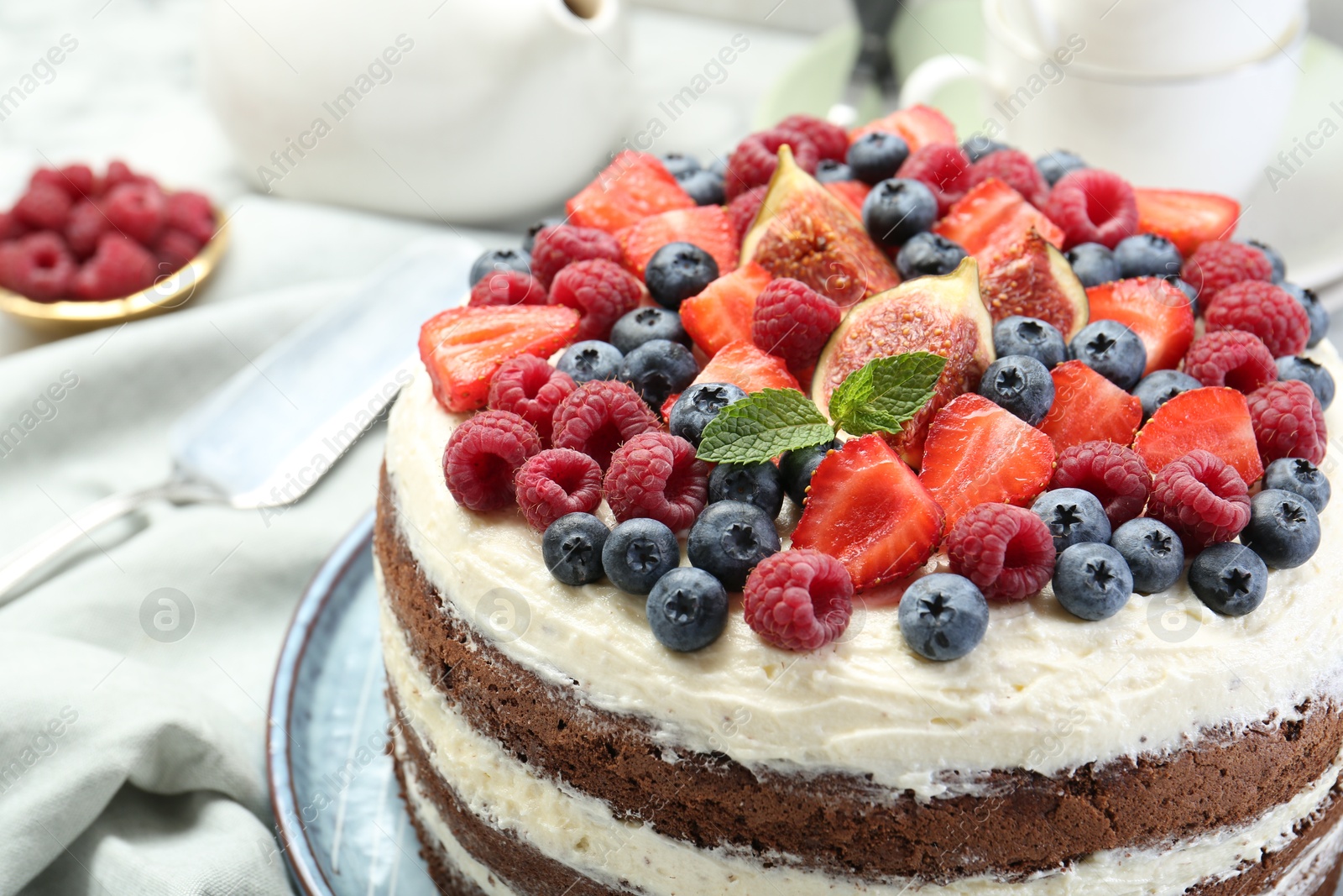 Photo of Delicious chocolate sponge cake with berries served on white table, closeup