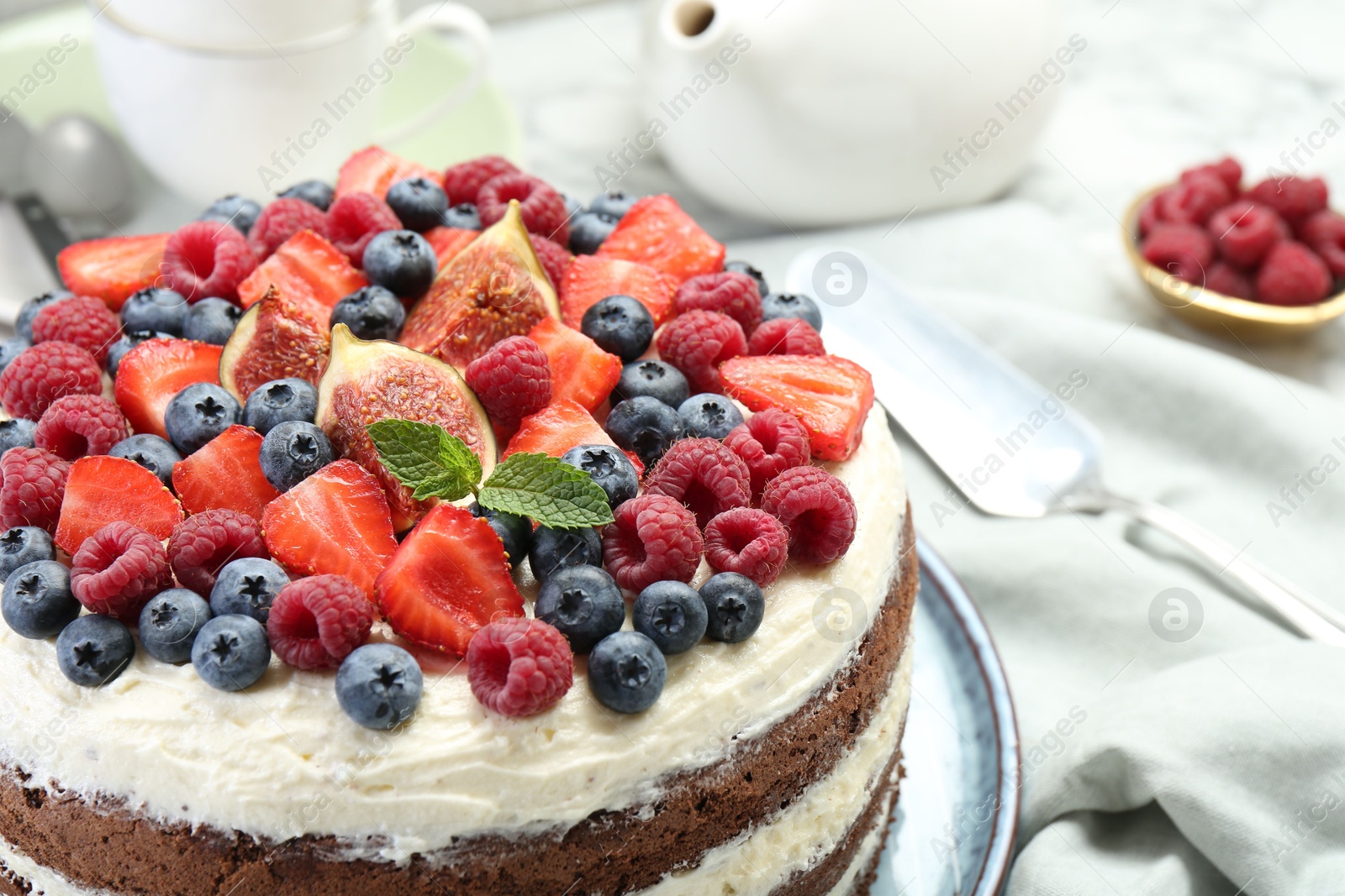 Photo of Delicious chocolate sponge cake with berries served on white table, closeup