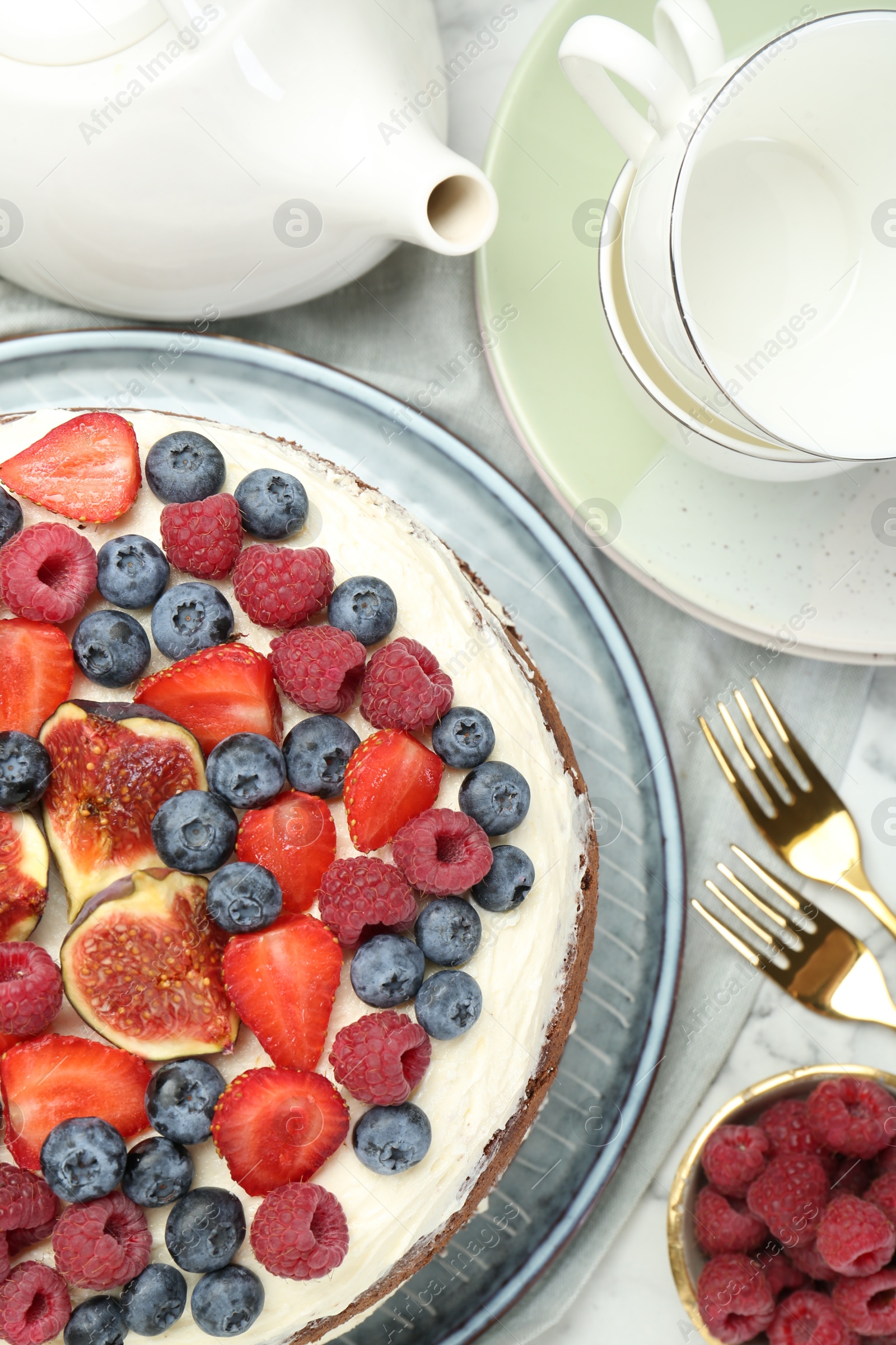 Photo of Delicious chocolate sponge cake with berries served on white table, flat lay