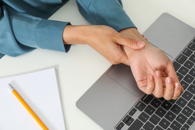 Photo of Carpal tunnel syndrome. Woman suffering from pain in wrist at desk, closeup