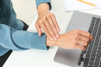 Photo of Carpal tunnel syndrome. Woman suffering from pain in wrist at desk, closeup