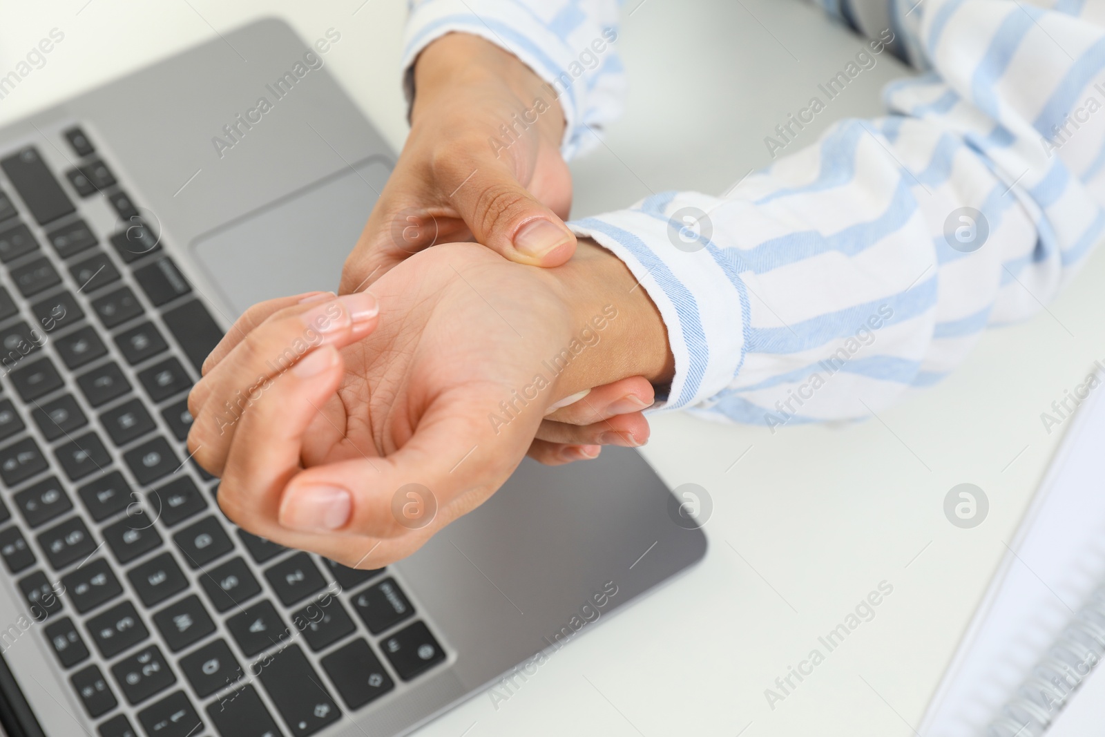 Photo of Carpal tunnel syndrome. Woman suffering from pain in wrist at desk, closeup