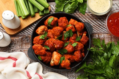 Photo of Baked cauliflower buffalo wings with parsley served on wooden table, flat lay