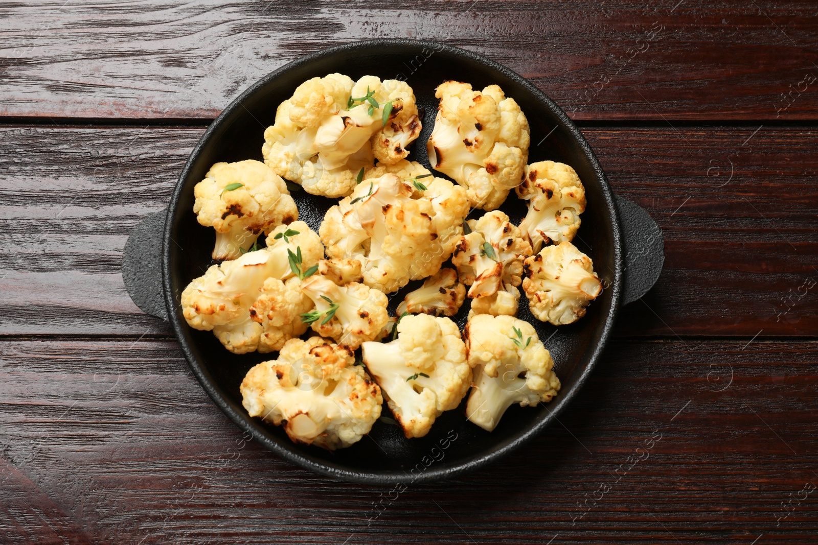 Photo of Tasty baked cauliflower in baking pan on wooden table, top view