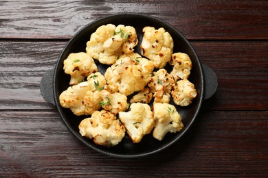 Photo of Tasty baked cauliflower in baking pan on wooden table, top view