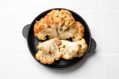 Photo of Tasty baked cauliflower in baking pan on white tiled table, top view