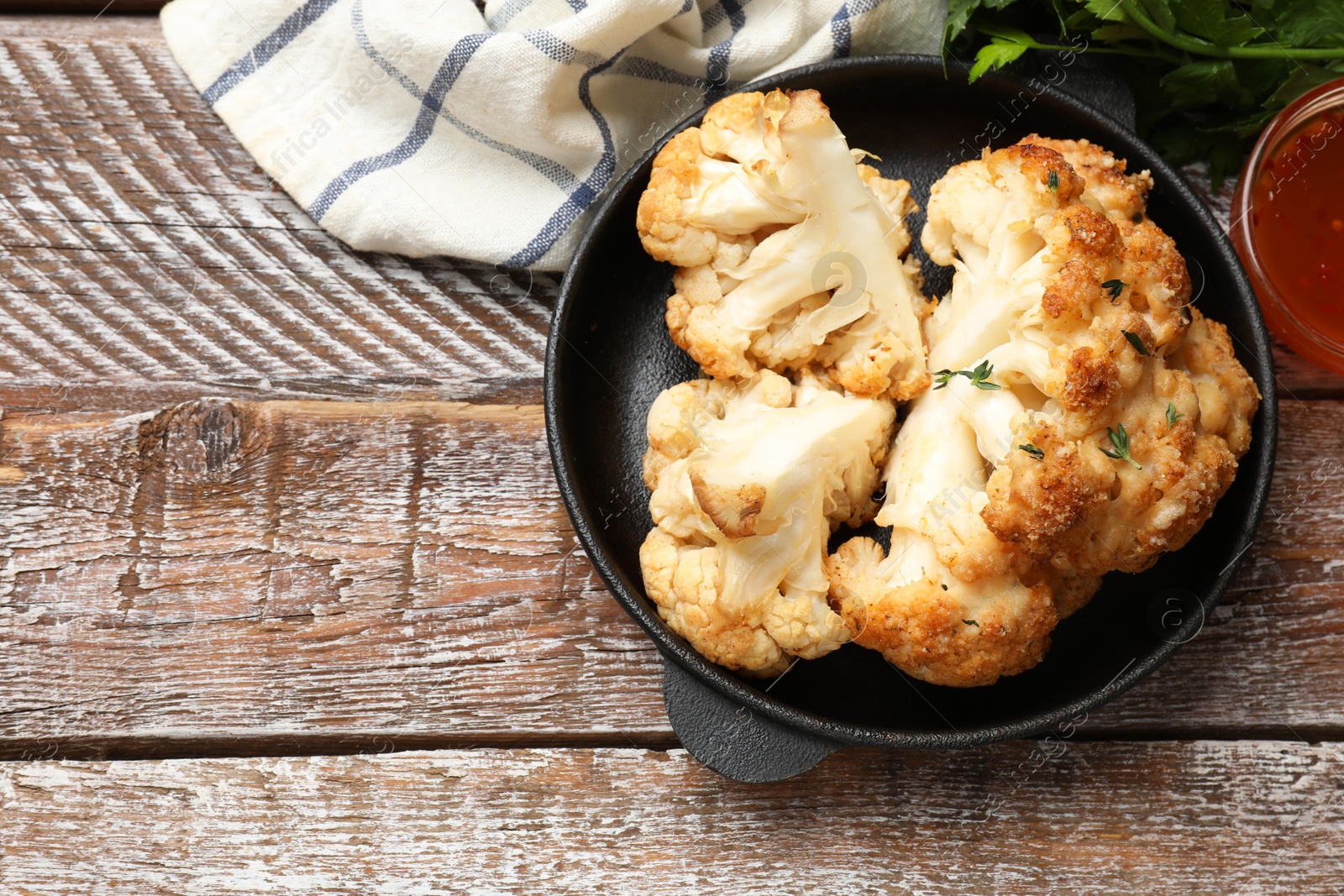 Photo of Tasty baked cauliflower in baking pan on wooden table, flat lay. Space for text