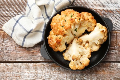 Photo of Tasty baked cauliflower in baking pan on wooden table, top view