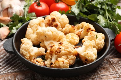 Photo of Baked cauliflower and products on wooden table