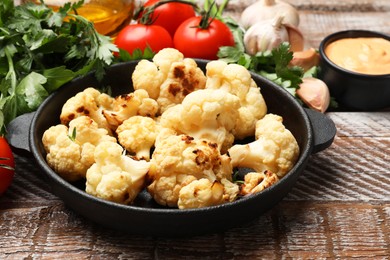 Baked cauliflower, sauce and products on wooden table