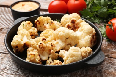 Photo of Baked cauliflower, sauce and products on wooden table, closeup