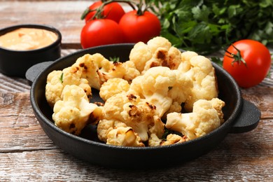 Photo of Baked cauliflower, sauce and products on wooden table