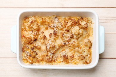 Photo of Tasty baked cauliflower in baking dish on light wooden table, top view