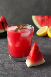 Photo of Tasty watermelon drink in glass, fresh fruits and mint on grey table