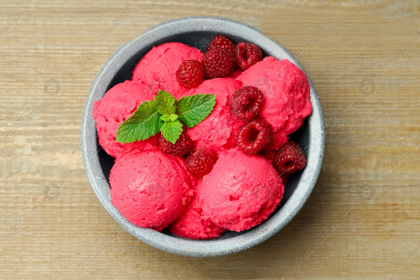 Photo of Delicious raspberry sorbet, fresh berries and mint in bowl on wooden table, top view