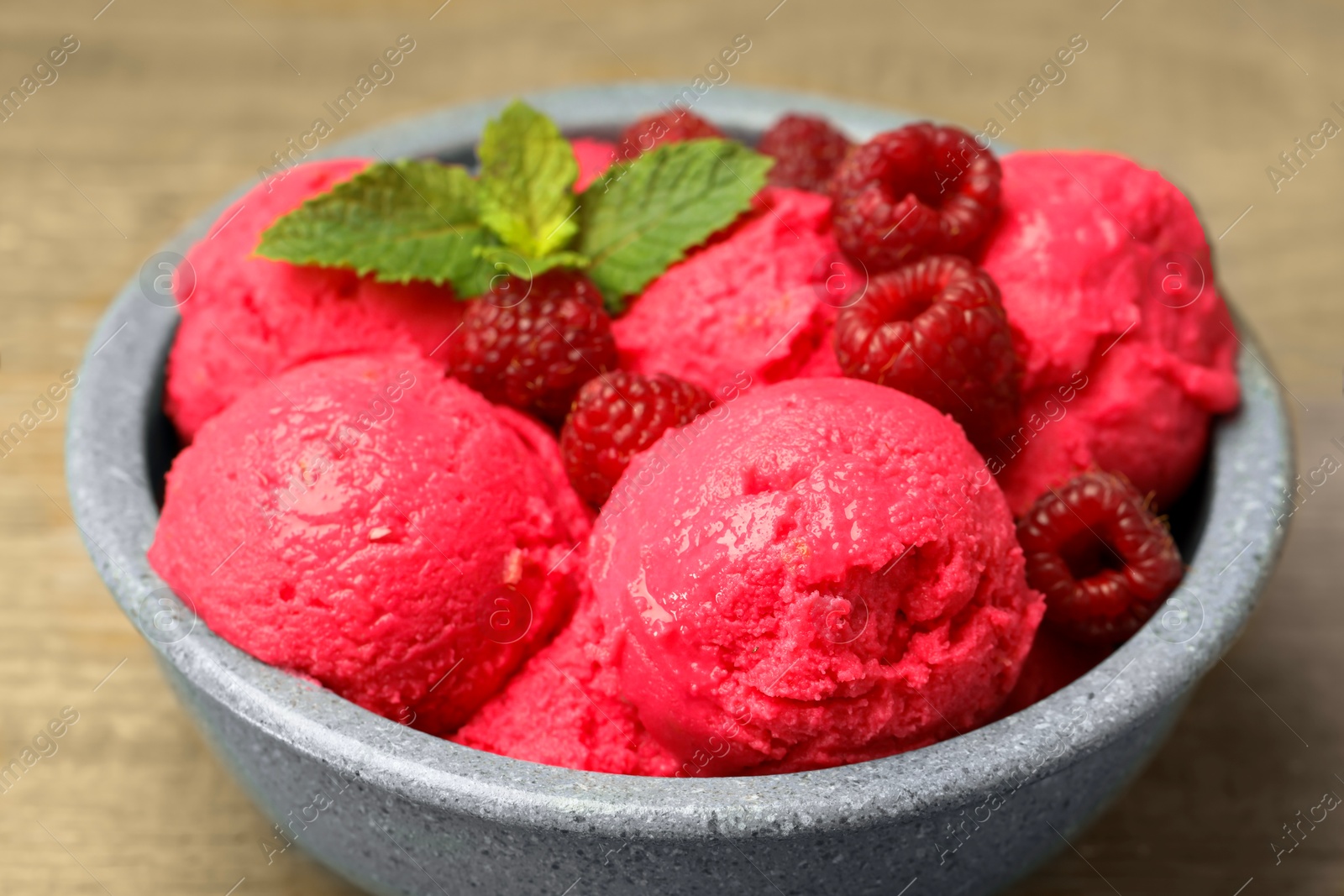 Photo of Delicious raspberry sorbet, fresh berries and mint in bowl on light table, closeup