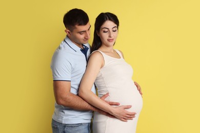 Photo of Beautiful pregnant woman with her husband on yellow background