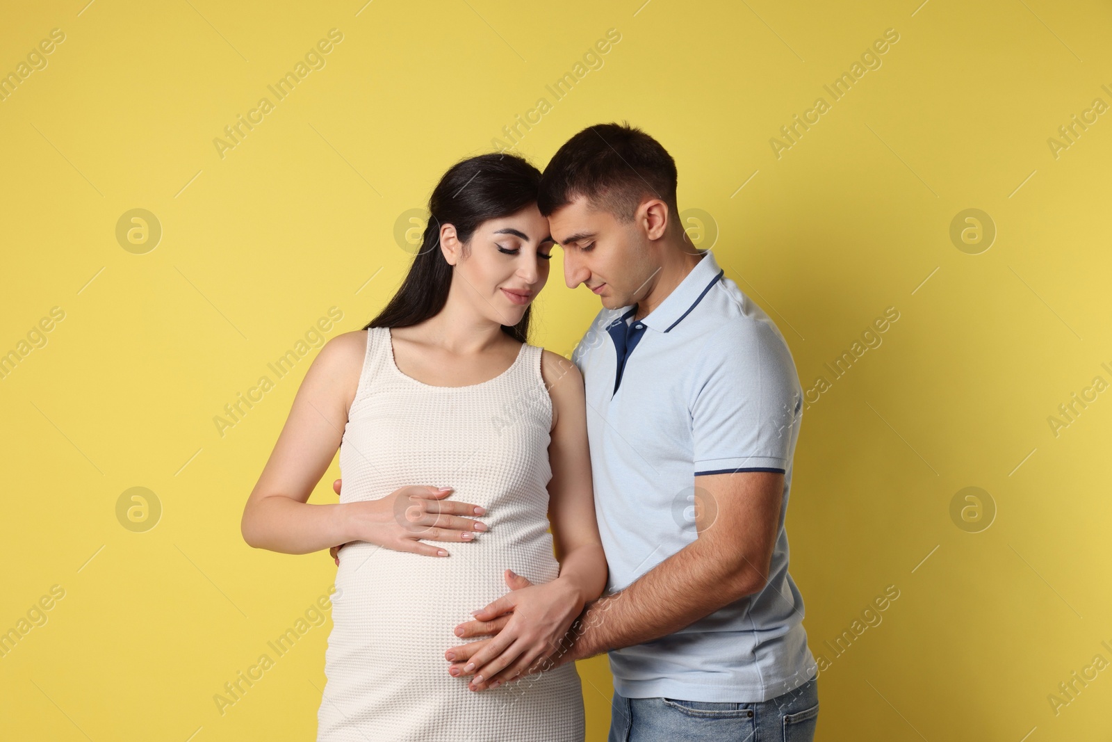 Photo of Beautiful pregnant woman with her husband on yellow background