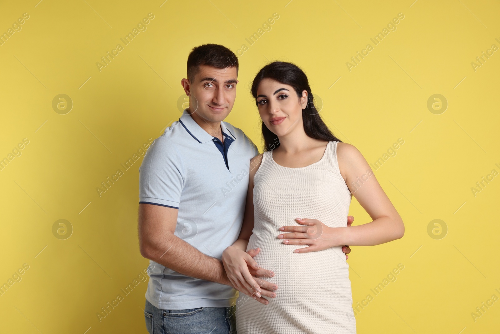 Photo of Beautiful pregnant woman with her husband on yellow background