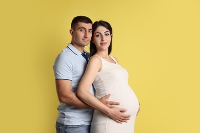 Photo of Beautiful pregnant woman with her husband on yellow background