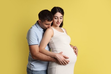 Photo of Beautiful pregnant woman with her husband on yellow background