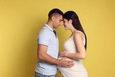 Photo of Beautiful pregnant woman with her husband on yellow background