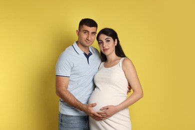 Photo of Beautiful pregnant woman with her husband on yellow background