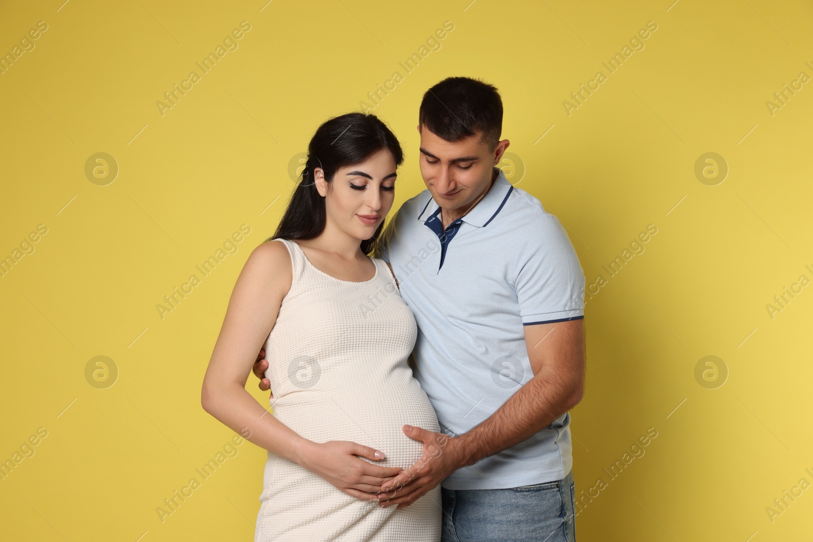 Photo of Beautiful pregnant woman with her husband on yellow background