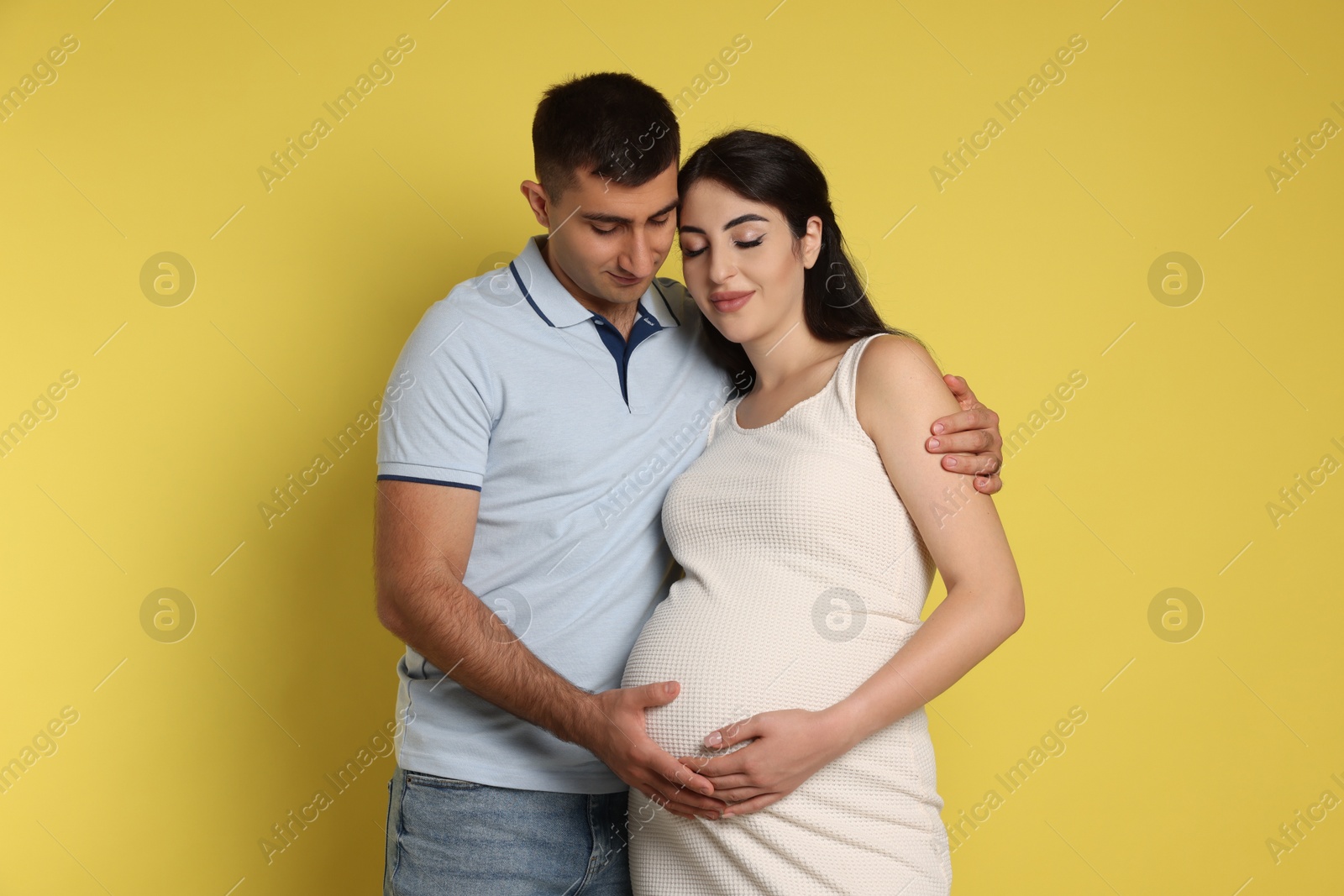 Photo of Beautiful pregnant woman with her husband on yellow background