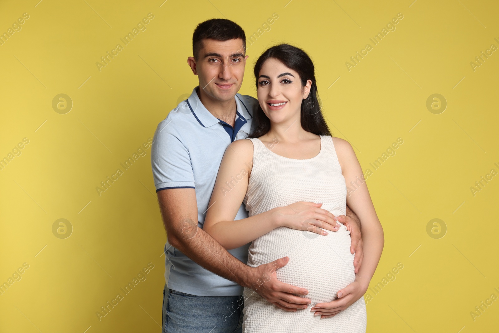 Photo of Beautiful pregnant woman with her husband on yellow background