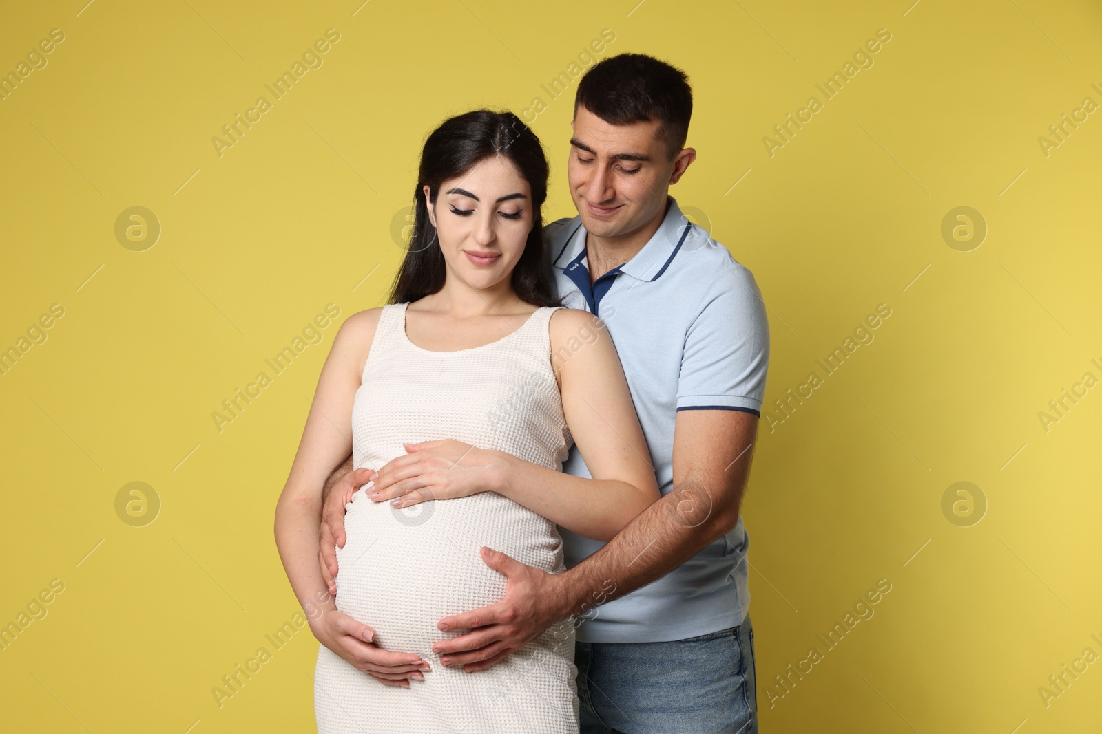 Photo of Beautiful pregnant woman with her husband on yellow background