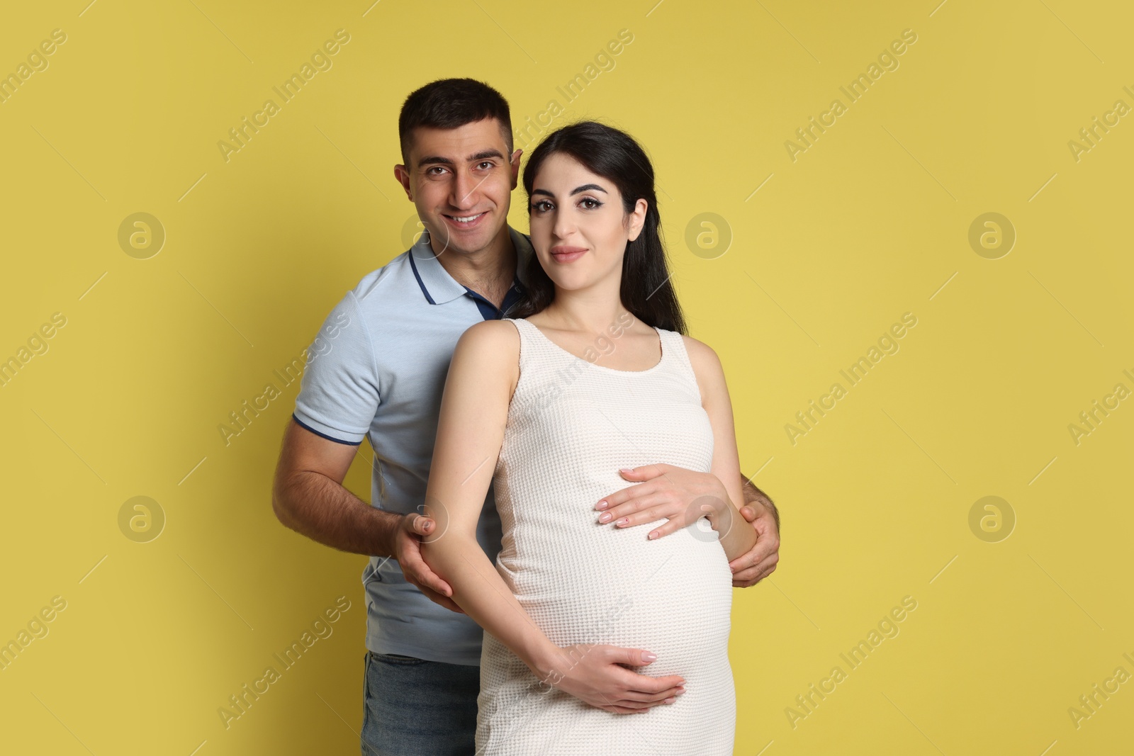 Photo of Beautiful pregnant woman with her husband on yellow background