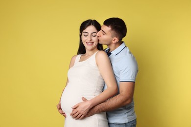 Photo of Beautiful pregnant woman with her husband on yellow background