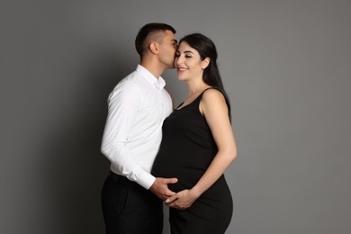 Photo of Beautiful pregnant woman with her husband on grey background