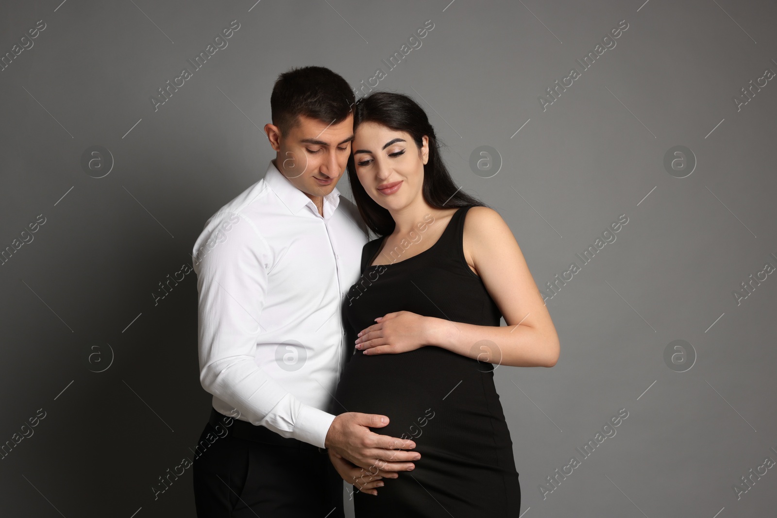 Photo of Beautiful pregnant woman with her husband on grey background