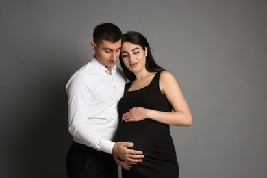 Photo of Beautiful pregnant woman with her husband on grey background